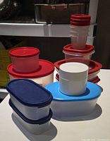 group of Tupperware storage containers with lids in various sizes and colors