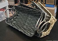 Stack of rectangular wicker trays in grey and natural tones with metal ring handles