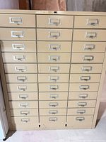 Full front view of beige steel cabinet showing 33 drawers