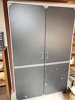 Front view of closed gray metal cabinet with two doors and handles