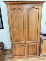 Front view of closed oak cabinet showing four doors and brass knobs