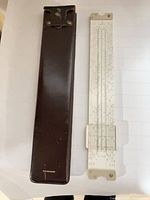 Slide rule next to brown leather case