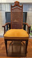 Front view of the pecan armchair showing cane back, upholstered seat, arms and legs