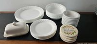 Overall lot view showing Corelle plates, bowls, butter dish and coasters