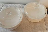Two CorningWare French White round casserole bakers with lids