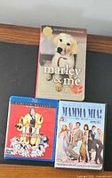 Group shot: Marley & Me book, 101 Dalmatians Blu-ray+DVD case, Mamma Mia! DVD case