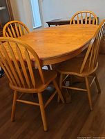 Oak oval dining table with four chairs around it