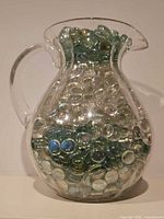 Front view of glass pitcher filled with beads