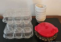 Group view of all items: stacked glass jars in case, stack of bowls, red cheese baker on crystal ashtray