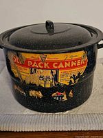 Exterior of black speckled enamelware canner with lid and partial Ole Pack label