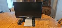 Front view of Haier 22" TV with remote, adapter and manual on table