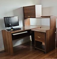 Overall view of corner desk with hutch, monitor, keyboard and file cabinet