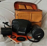 Tan leather camera bag, Konica camera and lens cases, manual, caps