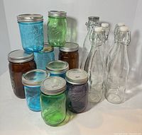 Group view of nine colored Ball jars and five swing-top bottles