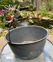Front view of gray graniteware kettle showing exterior surface, bail handle and wood grip