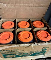 Open box showing six stacks of orange dome clay targets