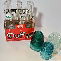 Six Duffy's bottles in carrier with three Hemingray insulators