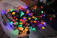 Tangled string of multi-coloured LED lights on green wire showing bulb shapes and colours