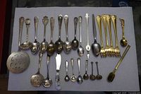 Full layout of 26 silver and gold plate flatware pieces on surface