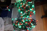Two intertwined strings of red and green LED lights illuminated on tabletop