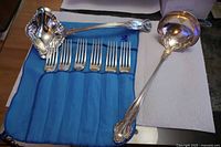 Forks in cloth roll with two ladles displayed