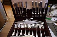 Open flatware chest showing knives in lid, spoons and forks below