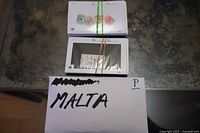 Two stacks of dealer cards bound with elastics and envelope marked Malta