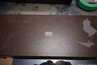 Exterior of brown Cross case showing logo and peeling at corner