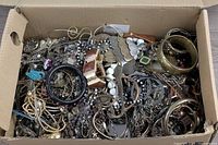 Overview of box filled with tangled costume jewelry pieces