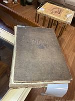 Front cover of large brown cloth-bound Illustrated London News volume with detached spine