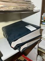 Two thick navy binders stacked on shelf