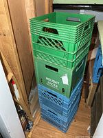 Stack of four plastic milk crates, two green on top of two blue