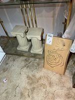 Pair of plaster pedestals alongside laser-cut wood slab bear art