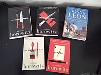 All five mystery novels laid out, cover fronts visible for identification