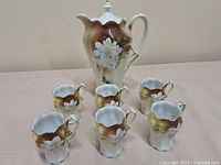 Full view of cocoa pot and six mugs