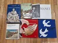 Six art books arranged on floor showing covers