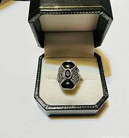 Front view of sterling ring in box showing amethyst center, onyx sides, marcasite detailing