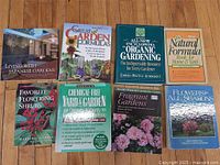 Eight gardening books laid out on wood floor