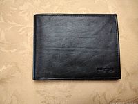 Front view of closed black leather wallet showing Fina logo