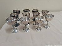 Front view of 11 metal goblets showing bowls and stems
