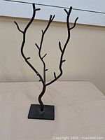 Full view of black metal branch jewelry holder on table
