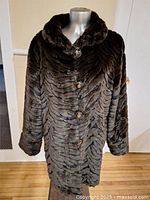 Full view of faux fur coat on mannequin showing front and buttons