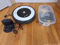 Roomba vacuum, dock and power cord, accessory bin visible