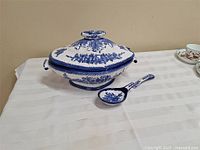 Tureen base, lid and ladle displayed on table
