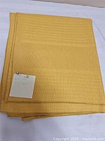 Folded golden yellow tablecloth with size note