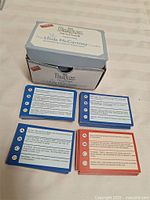Open box with multiple stacks of coloured trivia cards
