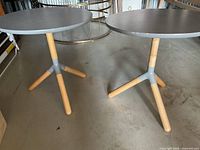 Two round grey-topped side tables with tripod legs