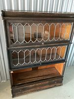 Front view of three-section barrister cabinet showing two leaded glass doors and open bottom section with drawer