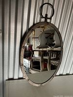 Full view of oval mirror with metal frame and ring hanger