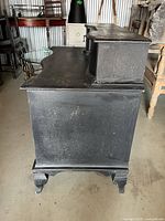 Left side view showing black painted wood dresser, serpentine shape, bracket feet